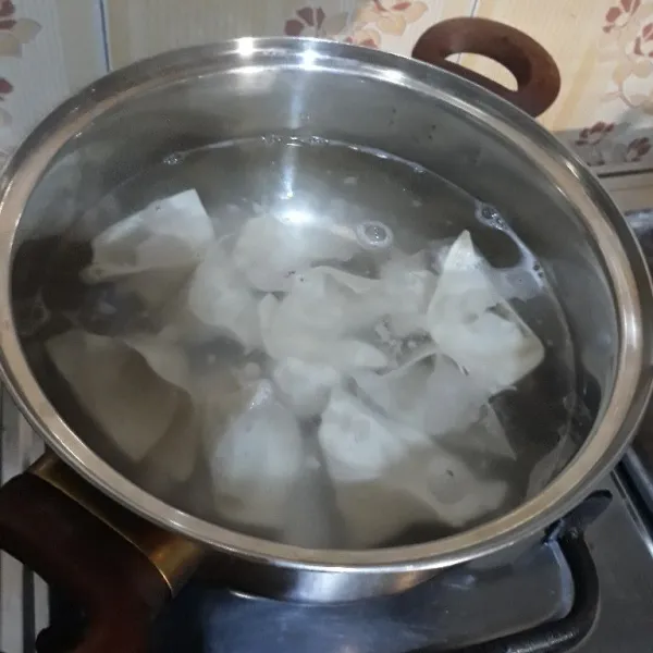 Rebus di air mendidih hingga matang dan mengapung. Angkat lalu masukkan ke dalam wadah dan beri sedikit air agar tidak menempel.