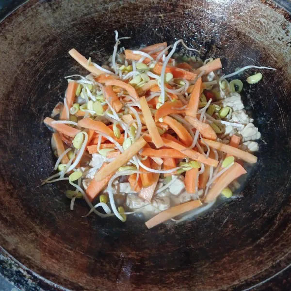 Masukkan wortel dan toge kedelai. Aduk rata. Masak hingga setengah matang.