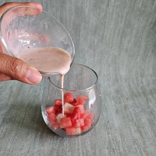 Campurkan yogurt dengan selai strawberry, kemudian tuang ½ bagian yogurt ke dalam gelas.