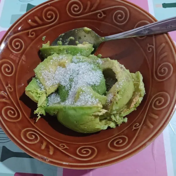 Keruk daging alpukat, tuang ke wadah. Tambahkan gula.