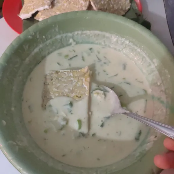 Panaskan minyak secukupnya, celupkan tempe ke dalam adonan terigu hingga terbalut rata.