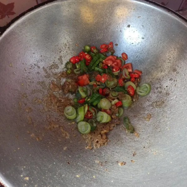 Setelah bumbu matang masukkan cabai rawit, tomat dan daun bawang, masak hingga layu dan matang.