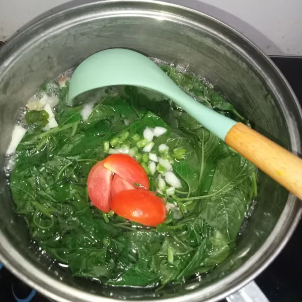 Setelah bayam mulai layu, masukkan potongan tomat dan daun bawang.