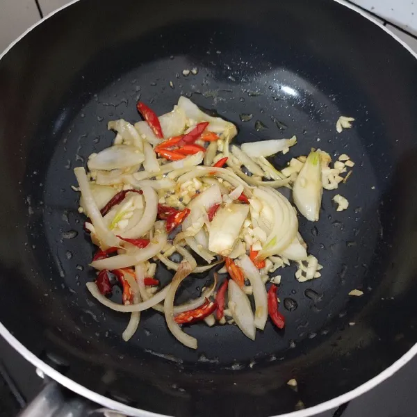 Tumis bawang bombay dan bawang putih hingga layu, tambahkan cabe, aduk rata.