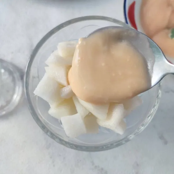 Tata buah pear dalam wadah saji, tuang dengan saos yogurt diatasnya.