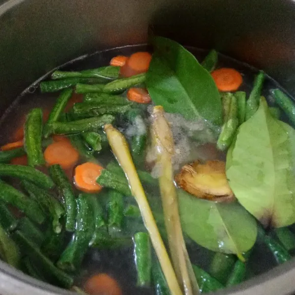 Rebus wortel, kacang panjang, daun salam dan serai hingga matang.