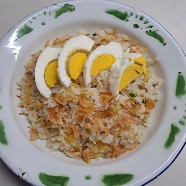 Ambil piring saji, beri nasi goreng secukupnya. Tambahkan irisan telur rebus dan bawang merah goreng secukupnya lalu sajikan.