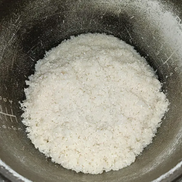 Cuci bersih beras dan masukkan ke dalam panci rice cooker.