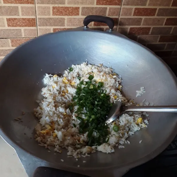 Masukkan nasi dan daun bawang, aduk rata.