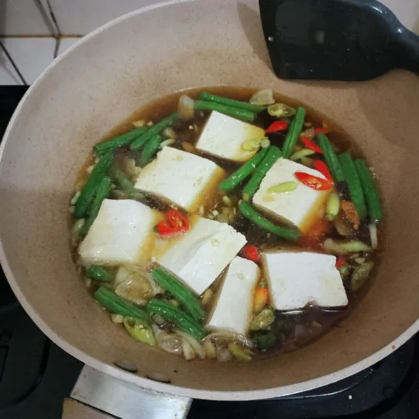 Tambahkan air, lalu masukkan tahu, cabai, dan kacang panjang.