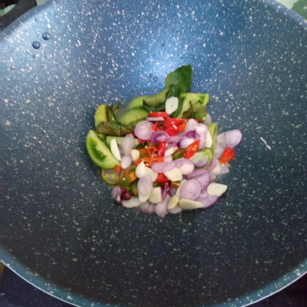 Panaskan minyak, masukkan bawang merah, bawang putih, cabe merah, cabe rawit, daun jeruk, daun salam dan tomat hijau.