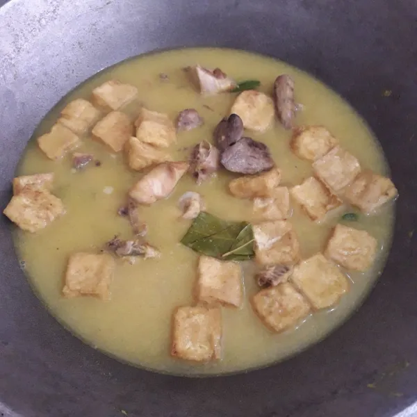 Masukkan ayam dan tahu. Aduk-aduk. Tambahkan air. Rebus sampai air mendidih.