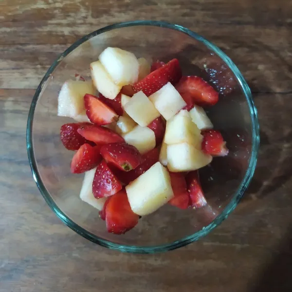 Masukkan potongan apel dan strawberry ke dalam mangkuk saji.