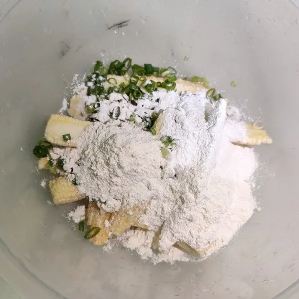 Masukkan daun prei, sejumput merica bubuk, dan tepung ke dalam wadah baby corn
