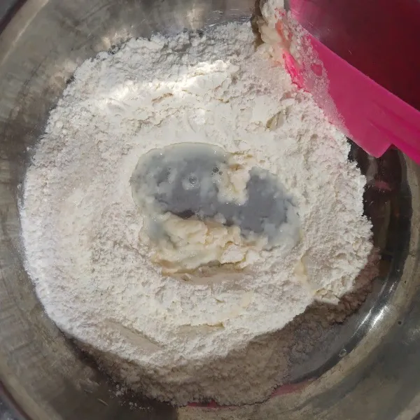 Campur tepung terigu, gula, garam, susu bubuk, vanili bubuk dan baking powder. Buat lubang di tengah. Masukkan air panas bertahap sambil diaduk dengan spatula.