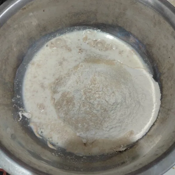 Masukkan tepung terigu, gula pasir, ragi instan, dan susu cair ke dalam wadah. Aduk hingga setengah kalis.