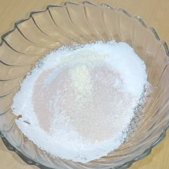 Masukkan gula pasir, ragi, bubuk susu dan sejumput garam, aduk adonan kering hingga merata