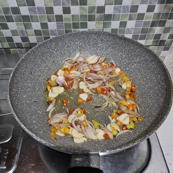 Tumis cabe rawit, bawang merah, dan bawang putih yang sudah di iris tipis hingga wangi dan layu.
