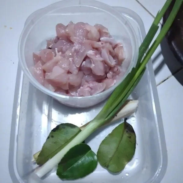 Potong ayam bentuk dadu ukuran kecil, iris daun bawang, geprek serai, dan sobek daun jeruk.