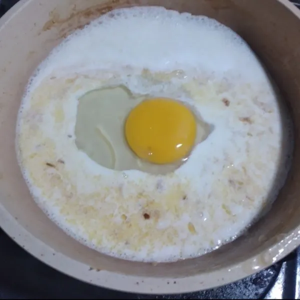 Pecahkan telur di tengah wajan, aduk hingga pecah dan tercampur dengan kuah susu.