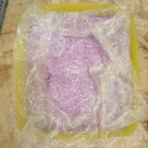 Lapisi permukaan es krim dengan plastik cling wrap menempel pada permukaan adonan es krim. Hal ini agar es krim nantinya lembut dan mencegah terbentuknya kristal es. Simpan dan bekukan di freezer selama minimal 6 jam atau semalaman.