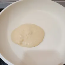 Tuang satu sendok sayur adonan ke dalam pan anti lengket . Tutup dan biarkan sisinya matang.