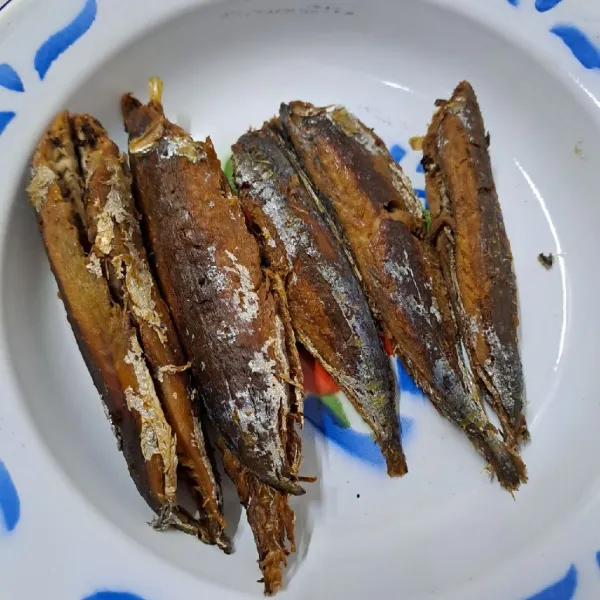 Bersihkan kotoran perut ikan pindang dan buang kepalanya. Kemudian goreng sampai matang, buang duri ikan lalu sisihkan.