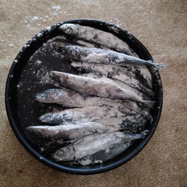 Cuci ikan pindang, lalu beri taburan tepung terigu.