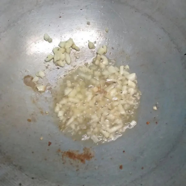 Tumis bawang putih cincang dengan menggunakan minyak ayam.