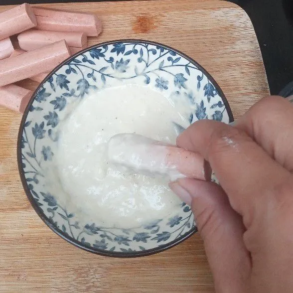 Celupkan sosis yang tidak dibelah ke dalam adonan tepung.