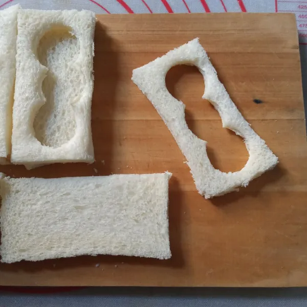 Potong tiap lembar roti menjadi dua. Salah satunya buat lubang di tengah.