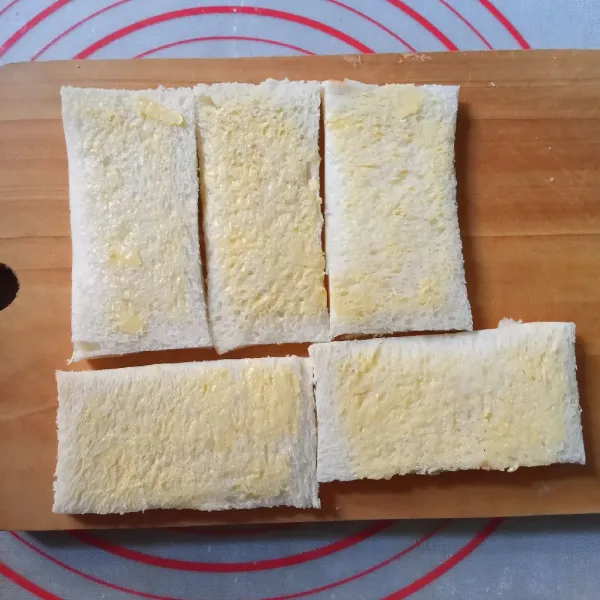 Oles salah satu lembar roti yang tidak dilubangi dengan margarin tipis-tipis.