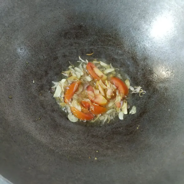 Tumis bawang merah dan bawang putih sampai layu dan harum, tambahkan tomat lalu aduk rata.