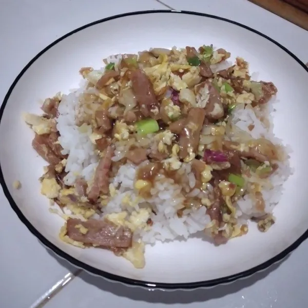 Tata nasi di piring saji, tambahkan tumisan sosis telur lalu siram dengan saus di atasnya.