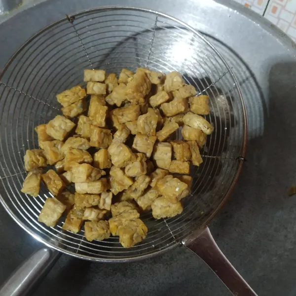 Potong dadu tempe lalu goreng sampai matang kemudian angkat dan tiriskan minyak.