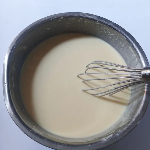 Tuang adonan telur ke dalam bahan kering, aduk sampai tercampur. Tuang susu bertahap sambil diaduk sampai licin, tutup dan diamkan selama 30 menit.