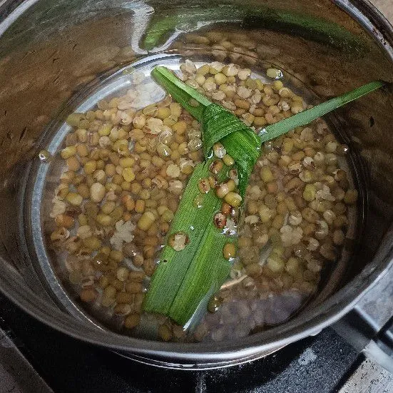 Rendam kacang hijau semalaman, lalu rebus hingga empuk dengan tambahan daun pandan agar wangi.