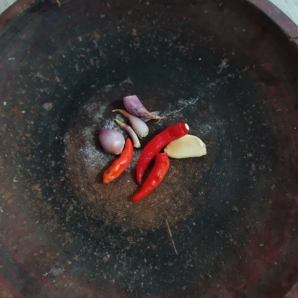 Masukkan cabe rawit, bawang putih dan bawang merah ke dalam sebuah cobek