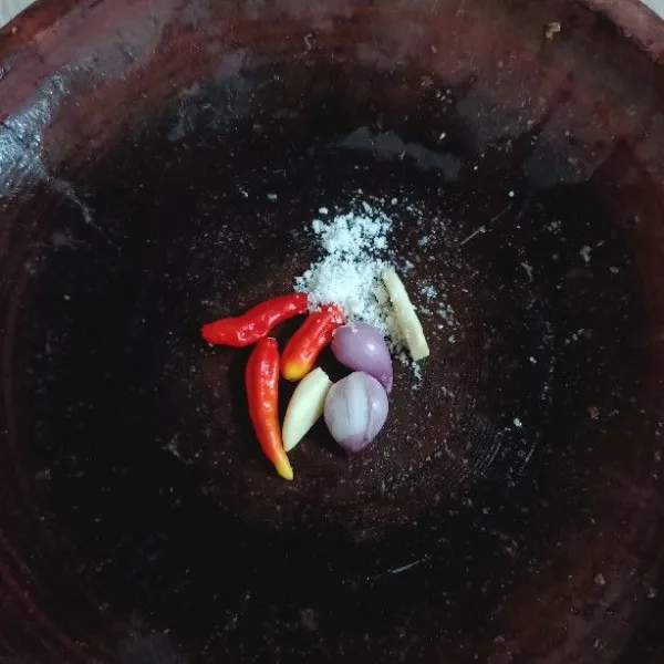 Masukkan bawang putih, bawang merah, cabai rawit, kaldu bubuk, dan garam dalam sebuah cobek.