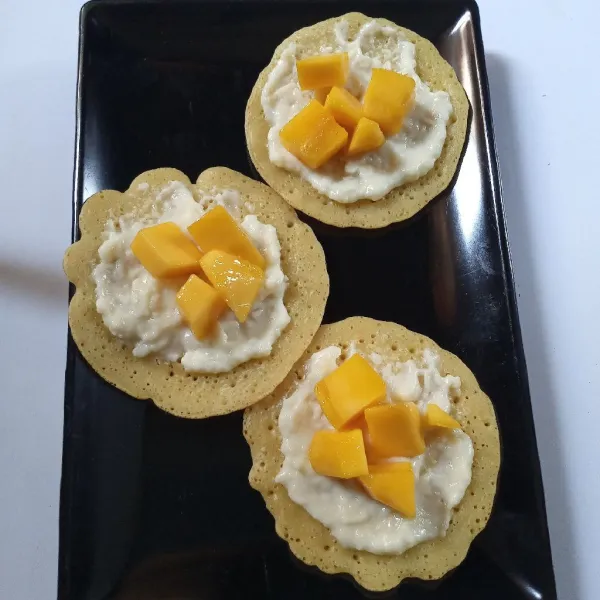 Oles tiap lembar pancake dengan krim keju, beri topping mangga dan siap disajikan.