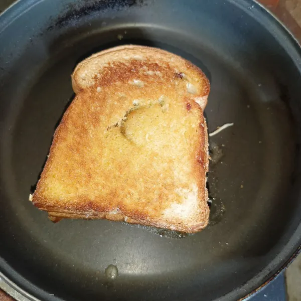 Panaskan margarin di pan, lalu letakkan roti dan panggang sampai kedua sisinya sedikit kecokelatan.