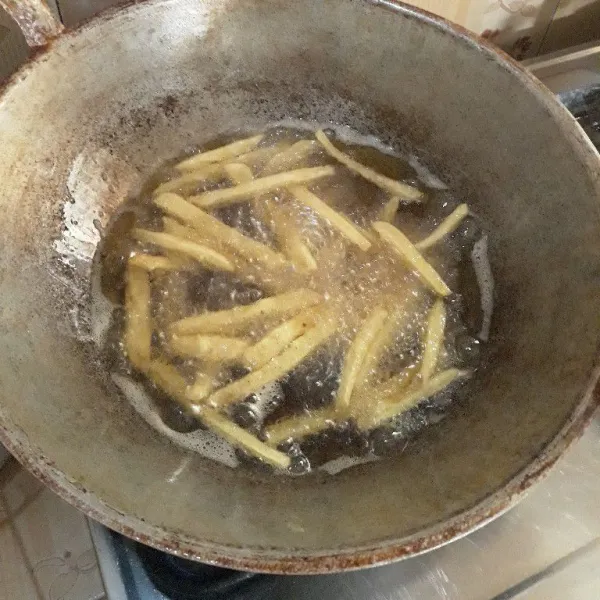 Panaskan minyak yang cukup banyak, lalu goreng kentang dengan api besar selama 3 menit dan dengan api sedang selama 3 menit lalu angkat dan tiriskan.