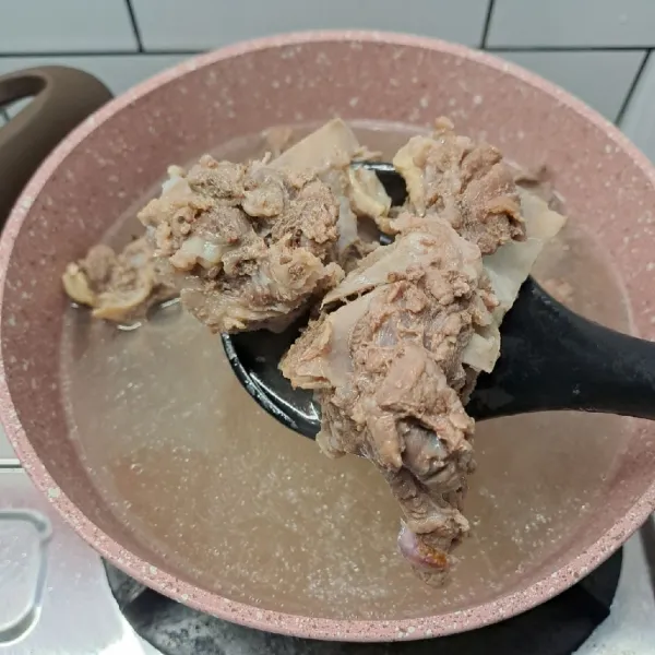 Masukkan tulang sapi, masak sampai empuk dagingnya, sambil dibuang kotoran busa hasil rebusan dagingnya. (Jika air mulai sedikit daging belum empuk tambahkan air panas secukupnya, lanjut masak sampai empuk).