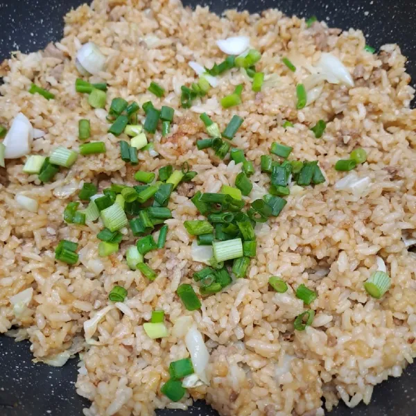 Masukkan daun bawang, masak sampai layu. Angkat dan sajikan nasi goreng dengan irisan telur, bawang merah goreng dan abon cabe.