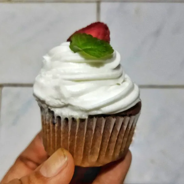 Hias menggunakan whipped cream dan topping dengan strawberry. Chocolate cupcakes siap untuk dihidangkan.