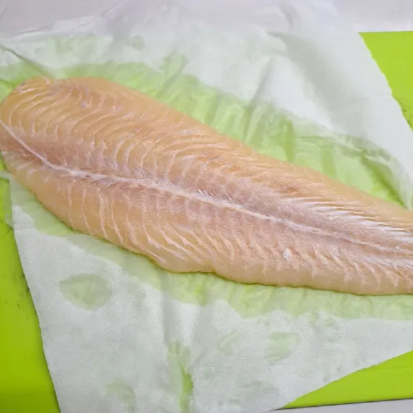 Keringkan ikan dori dengan tisu untuk mengurangi sisa air saat membilas ikan kemudian potong dadu.