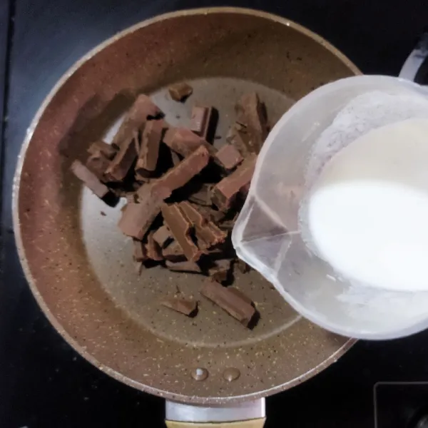Siapkan kompor induksi dan panci, kemudian masukkan potongan cokelat ke dalamnya. Tambahkan krim segar lalu panaskan dengan suhu yang paling rendah. Aduk menggunakan spatula hingga cokelat hampir meleleh semua, lalu angkat panci dari kompor.