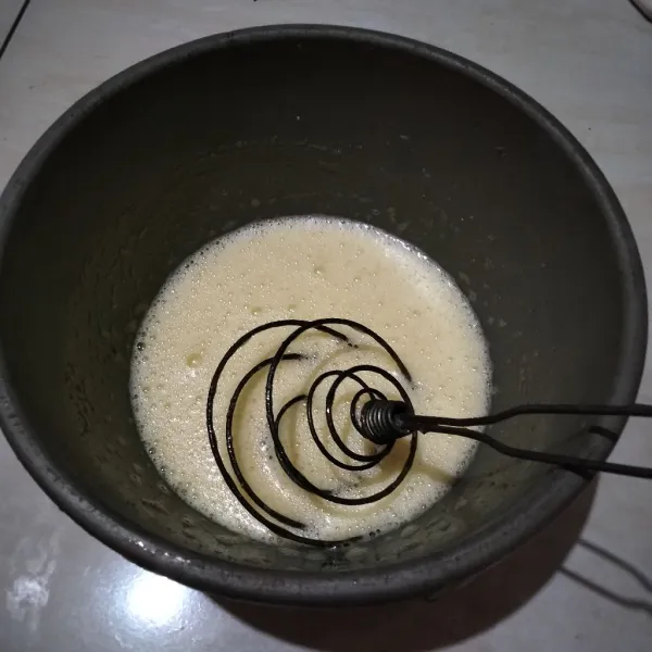 Campur gula pasir dan telur, kocok dengan whisk hingga gula larut.