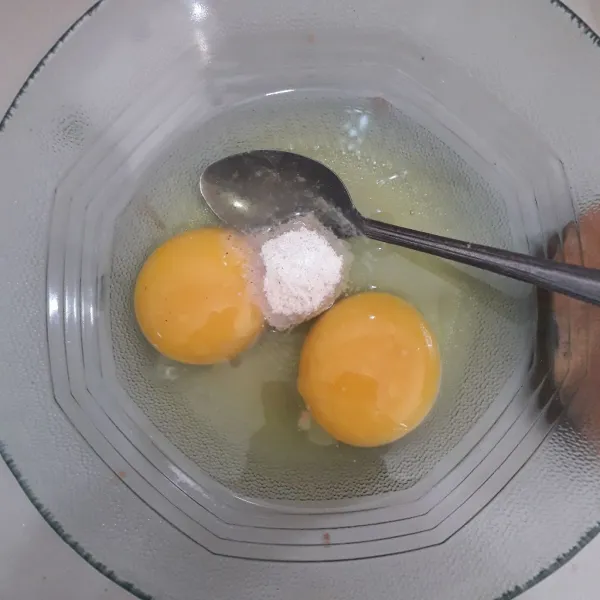 Pecahkan telur ke dalam mangkuk, tambahkan bumbu kaldu ayam bubuk lalu kocok lepas.