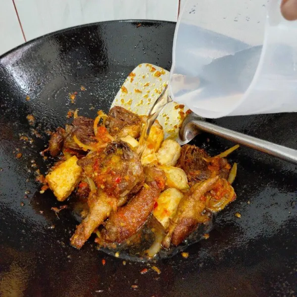 Masukkan ayam dan tahu, aduk rata lalu beri air.